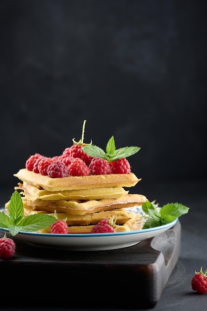 Stapel gebakken Belgische wafels met rijpe rode frambozen groene muntblaadjes