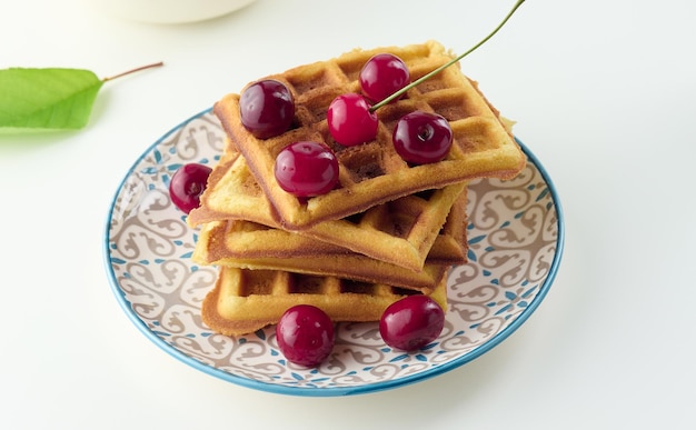 Stapel gebakken belgische wafels met rijpe rode kersen op de witte tafel breakfastx9