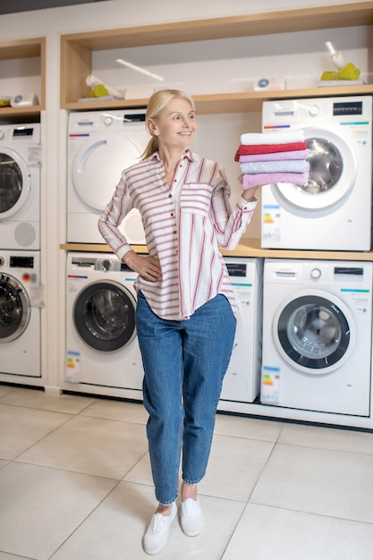 Stapel handdoeken. Glimlachende blonde vrouw permanent en met een stapel handdoeken