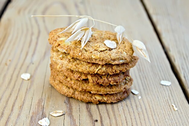 Stapel havermoutkoekjes met granen en een steel van haver op de achtergrond van houten planken