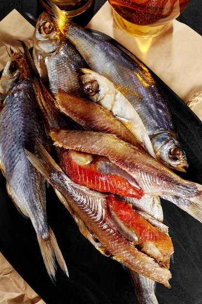 Stapel hele gezouten, aan de lucht gedroogde voorn en gevilde vis met kuit geserveerd op een zwart houten bord met amber pils. Traditionele Russische biersnack