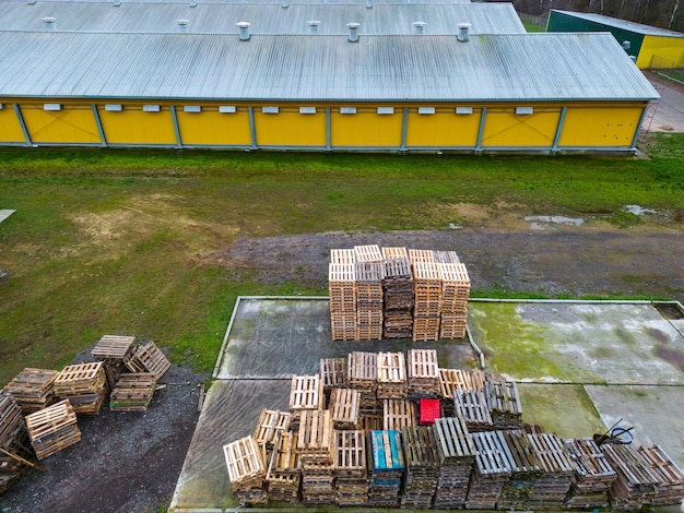 Stapel houten pallets luchtfoto Buitenruimte voor palletopslag onder het dak naast de kippenboerderij Stapels Eurotype-vrachtpallets bij een afvalrecyclingbedrijf