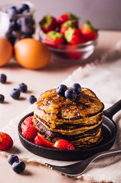 Stapel huisgemaakte pannenkoeken met bosbessen en aardbeien, perfect voor het ontbijt