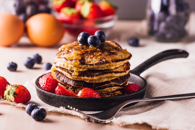 Stapel huisgemaakte pannenkoeken met bosbessen en aardbeien, perfect voor het ontbijt