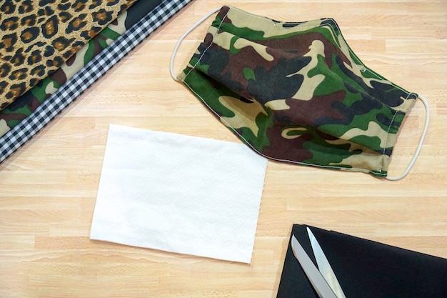 Stapel katoen, wit tissuepapier en doe-het-militaire camouflage gezichtsmasker op houten tafel
