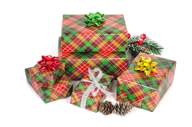 Stapel kerstdozen met geschenken in groen en rood geruit papier met strikken op een witte achtergrond