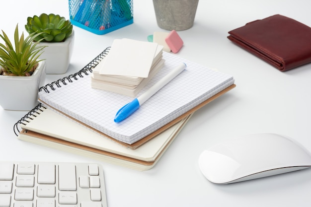 Stapel notebooks, groene planten in potten en een muis, werkplek van een freelancer