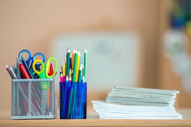 Stapel notitieboekjes, kleurrijke tekeningspotloden en kantoorbehoeftenregeling