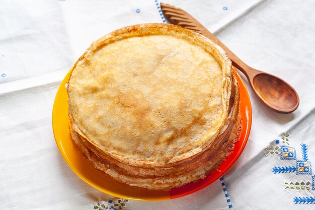 Stapel pannenkoeken Dunne pannenkoeken in een bord en een houten lepel Traditioneel rustiek eten