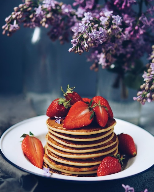 Stapel pannenkoeken met aardbeien op tafel.