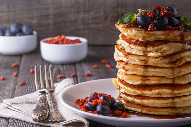 Stapel pannenkoeken met verse bosbessen, goji en ahornsiroop.