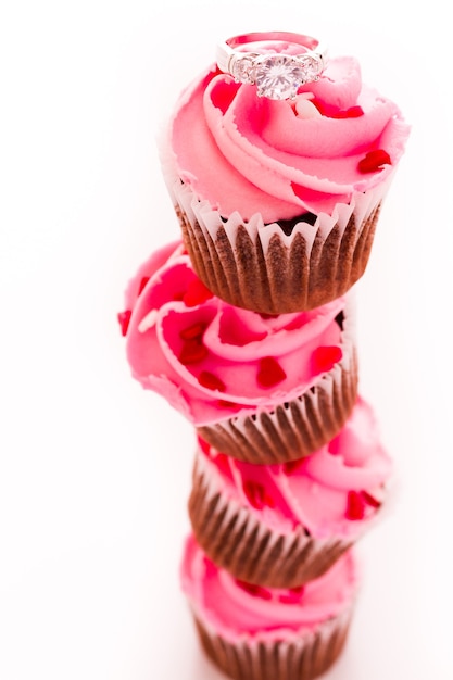 Stapel roze cupcakes met verlovingsring bovenop.