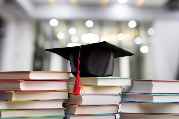 Stapel schoolboeken met zwarte afstudeerhoed