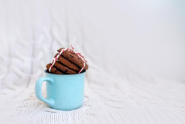 Stapel smakelijke chocolade kerstkoekjes op lichtgekleurde achtergrond Blauwe kop mok Afbeelding met selectieve focus ruiseffect en toning Bovenaanzicht