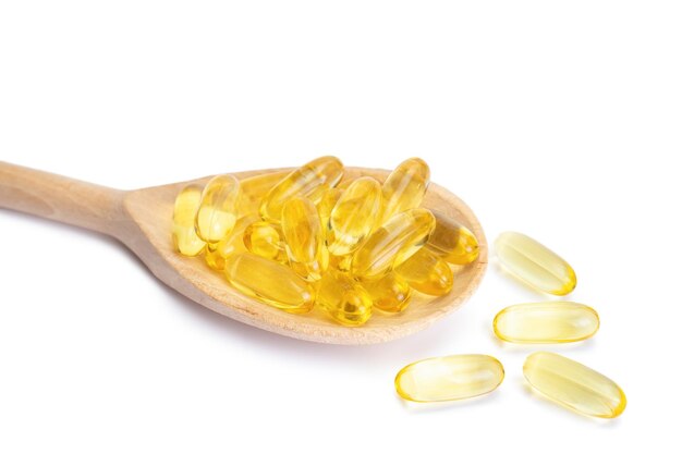 Stapel softgels capsules Omega 3 in houten lepel geïsoleerd op een witte achtergrond