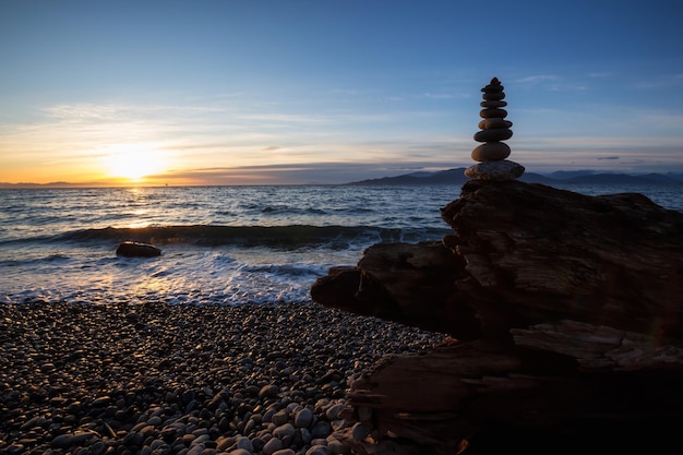 Stapel stenen opgestapeld bij de oceaan tijdens een zonnige zonsondergang