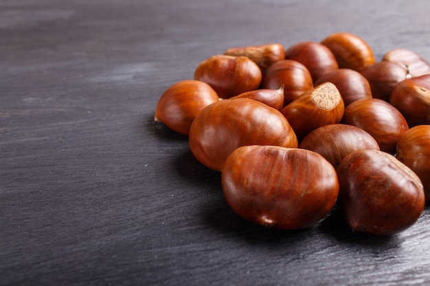 Stapel van zoete kastanjes op zwarte houten achtergrond