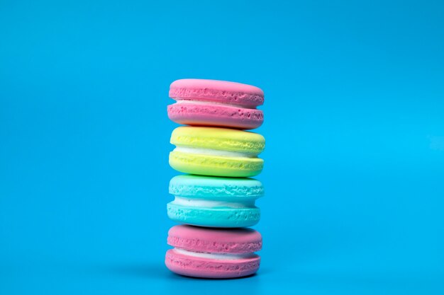 Stapel vers gebakken kleurrijke Franse bitterkoekjes op blauwe achtergrond kopie ruimte banner dessertcookiecak...