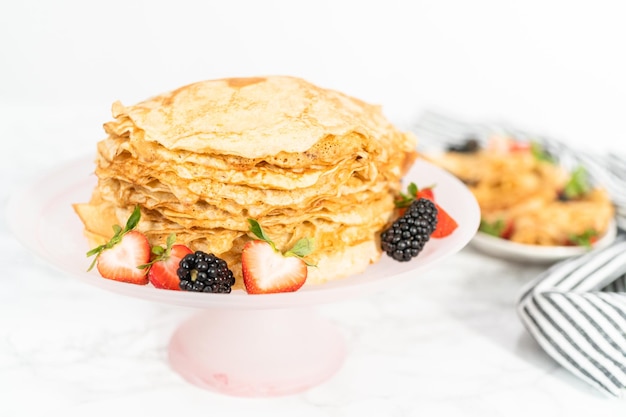 Stapel vers gebakken pannenkoeken met bessen op een taart staan.