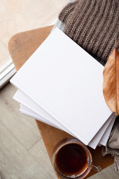 Stapel witte blanco boeken met herfstbladeren en een kop hete thee op een oud houten stoelmodel