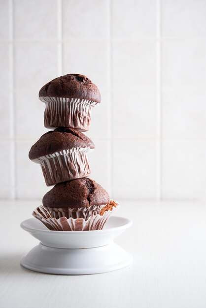 Stapel zelfgemaakte chocolade muffins in papieren bekers op een bord op keuken achtergrond close-up