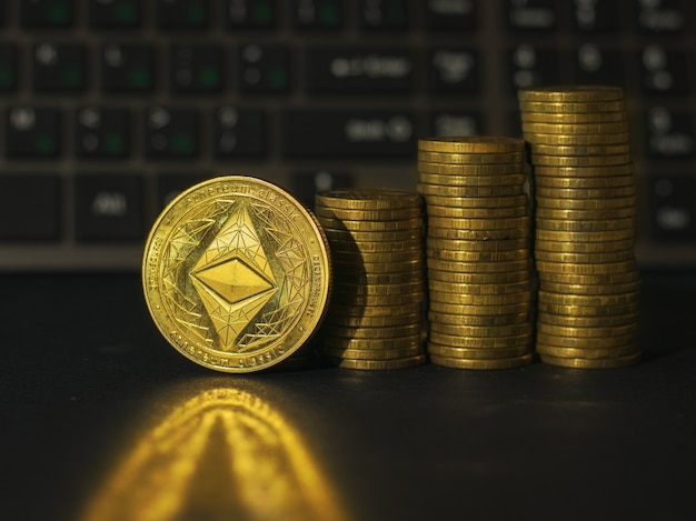 Stapels gouden munten en een metalen digitale munt op een zwarte achtergrond. Het concept van de stijging van de prijs van cryptocurrency.