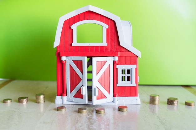 Foto stapels munten door rode huisminiatuur over groene achtergrond besparingen aanbetaling hypotheekconcepten