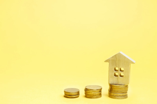 Stapels munten en een houten huis. het concept om geld te besparen voor het kopen van een huis