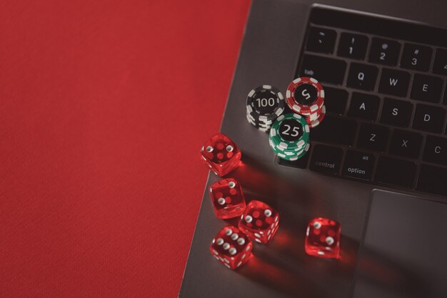 Stapels pokerfiches dobbelstenen en laptop op een rode achtergrond poker online concept