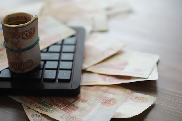 Stapels van 5000 roebelbankbiljetten op tafel naast de laptop Sparen en investeringen in de voorwaarden van sancties en inflatie