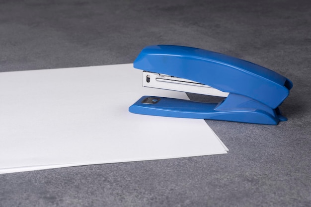 Stapler and sheets of white paper close up.