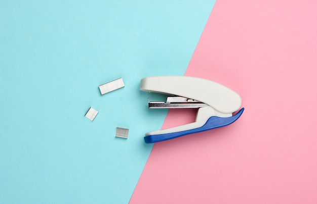 Stapler with paper clips on a blue-pink pastel.