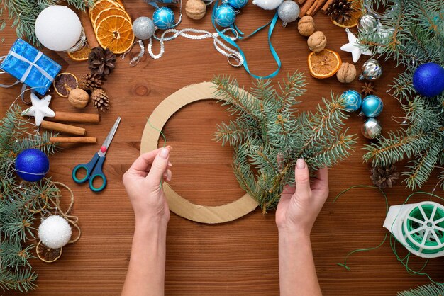 Stapsgewijs proces om thuis een kerstboomkrans te maken van vuren takken, sinaasappels en kerstballen