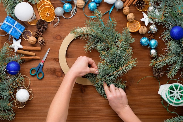 Stapsgewijs proces om thuis een kerstboomkrans te maken van vuren takken, sinaasappels en kerstballen