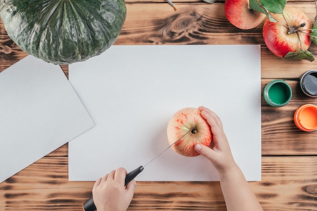 Stapsgewijze Halloween-tutorial voor kinderen met pompoen-appelprints. Stap 2: Snijd appel doormidden met mes, bovenaanzicht