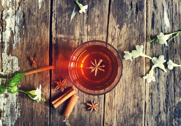 star anise in tea glass vibrant on wooden and cinnamon background, Top view