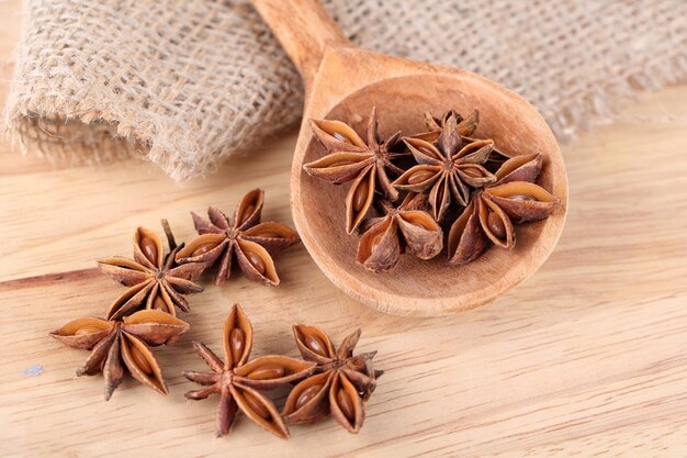 Star anise in wooden spoon, on wooden background