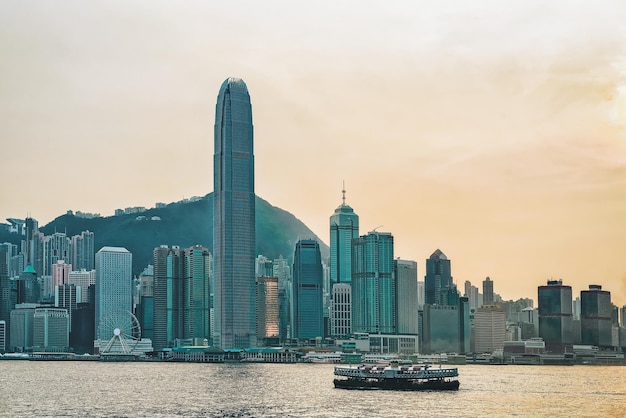 Star ferry nel porto di victoria e nell'orizzonte di hong kong al tramonto. vista da kowloon sull'isola di hong kong.