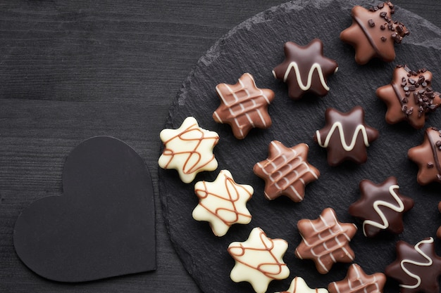 Star-shaped chocolates on dark textured background with black heart