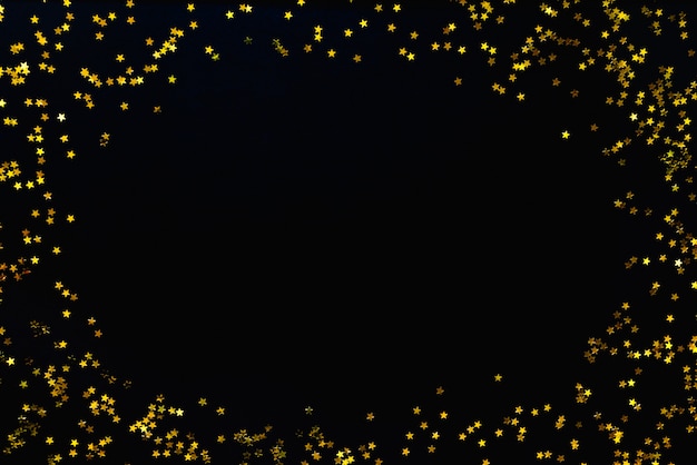 Star shaped golden sequins on a black background.