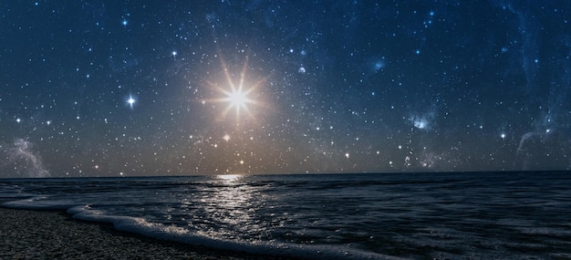 A star shines in the night sky over the sea on the holiday of christmas