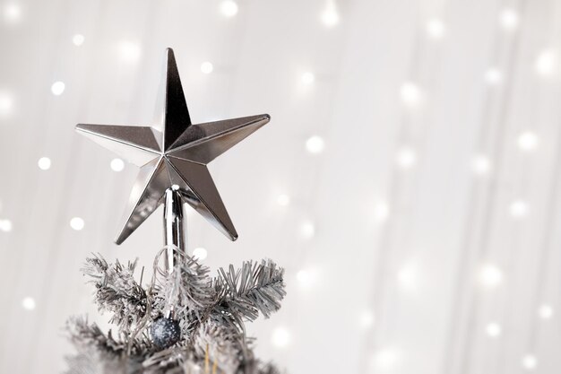 Star on top of christmas white tree bokeh background