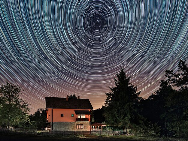 Star trails above the house residential building and the star\
trails on the sky