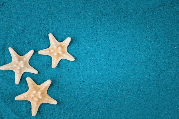 Starfish on the blue sand copy space. Colored sand.