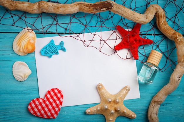 Starfish, pebbles and shells lying on a blue wooden background with postcard