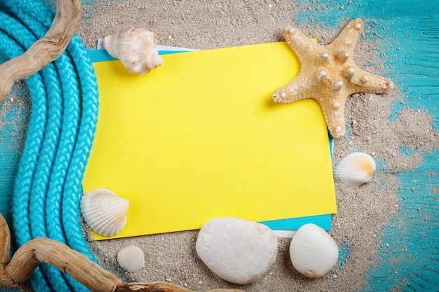 Starfish, pebbles and shells lying on a blue wooden surface with postcard