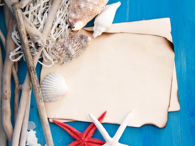 Foto stelle marine, legno stagionati, rete e conchiglie sulla vista superiore della parete di legno blu con lo spazio della copia su carta