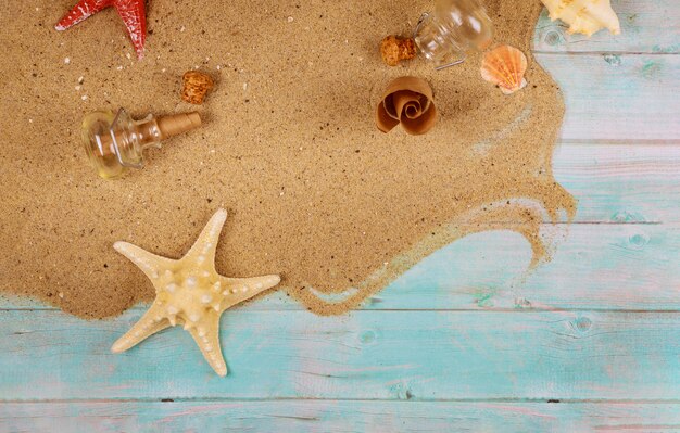 Starfish with seashells on sand on blue wooden surface