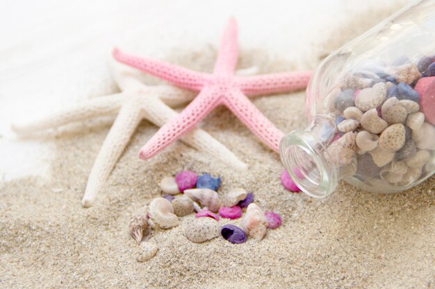 ヒトデと砂の上の瓶の中の色の海の貝をクローズアップ