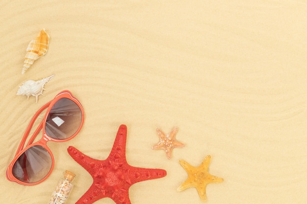 Starfishes, sunglasses and seashells on sand